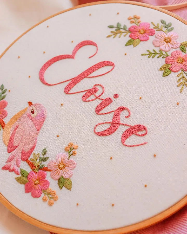 Custom embroidered floral clock showing pink flowers, bird, and name personalization
