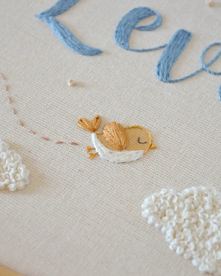 Embroidered design of a bird and clouds