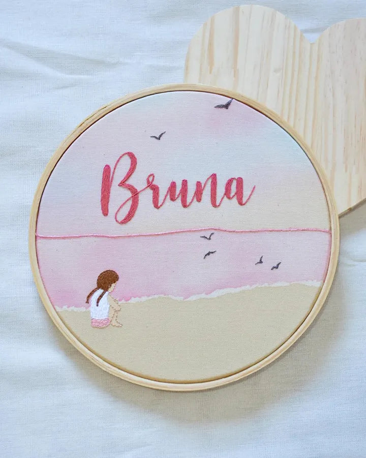 Embroidery hoop with 'Bruna' embroidered on a beach scene design.
