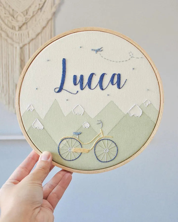 Embroidery hoop with 'Lucca' text and bicycle design