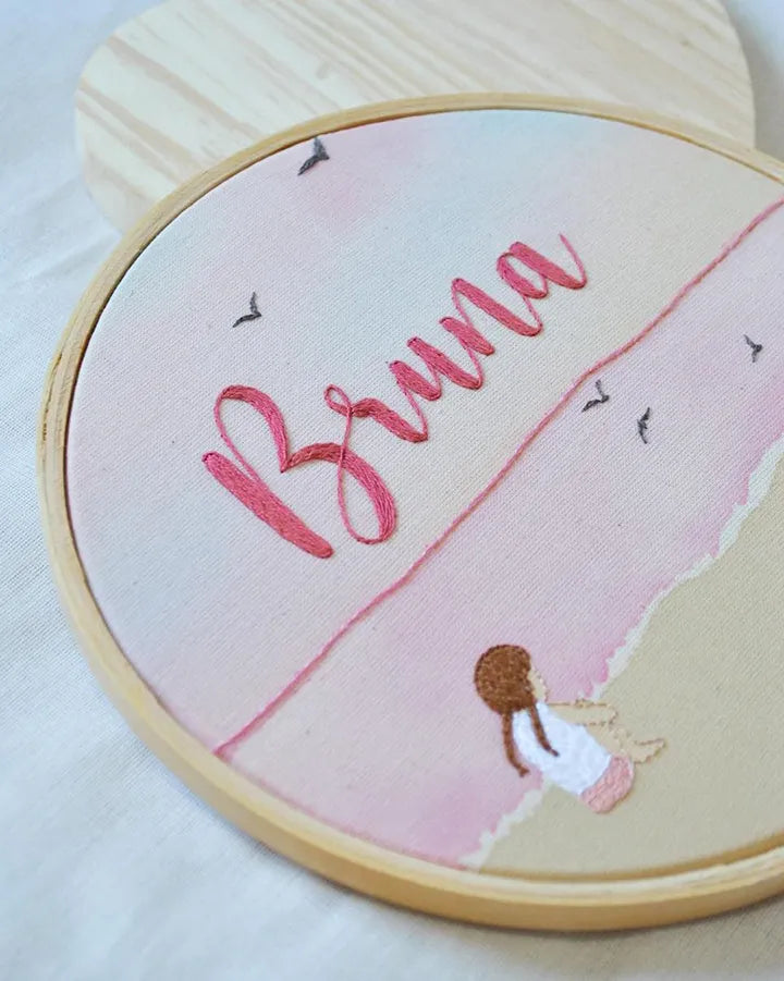 Embroidery hoop with a pink design and the name