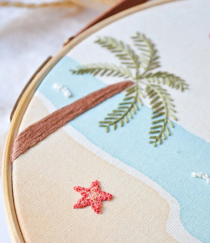 Embroidery hoop with a tropical scene including a palm tree and starfish