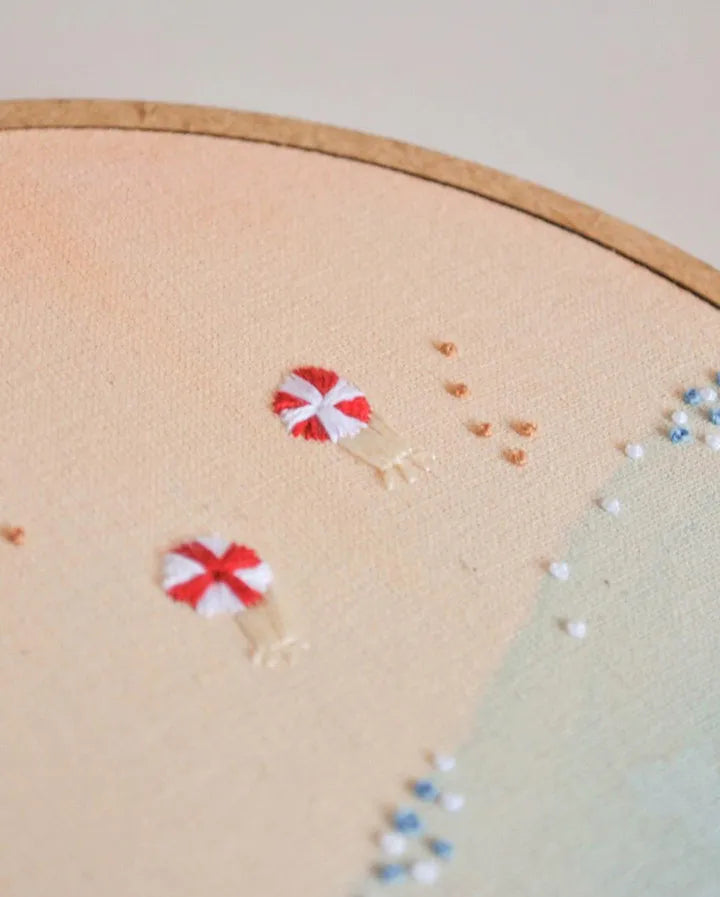 Embroidery hoop with red and white parasols