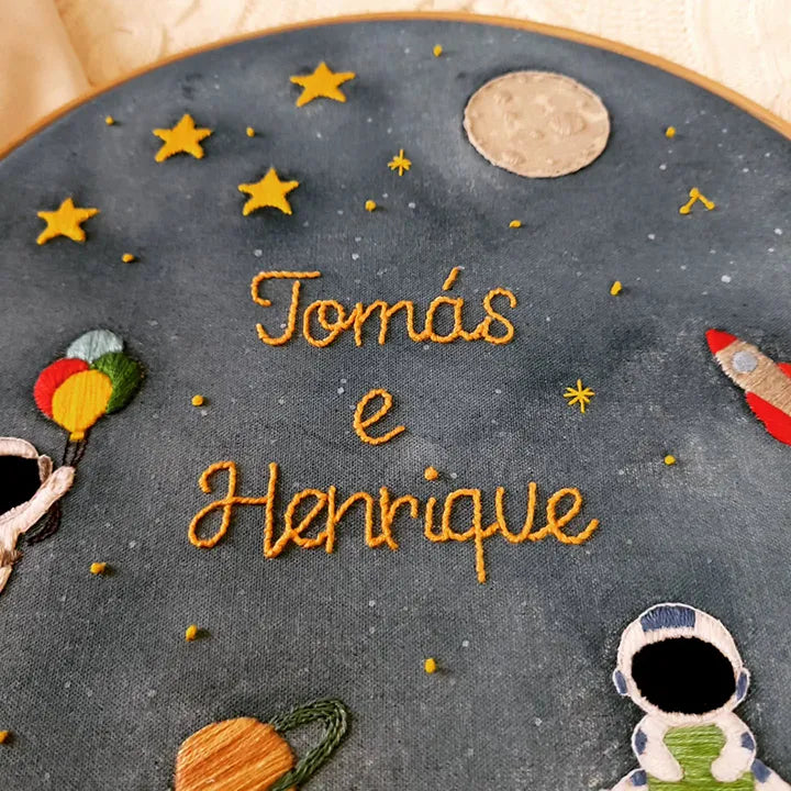 Embroidery hoop with space-themed decorations and embroidered twins names