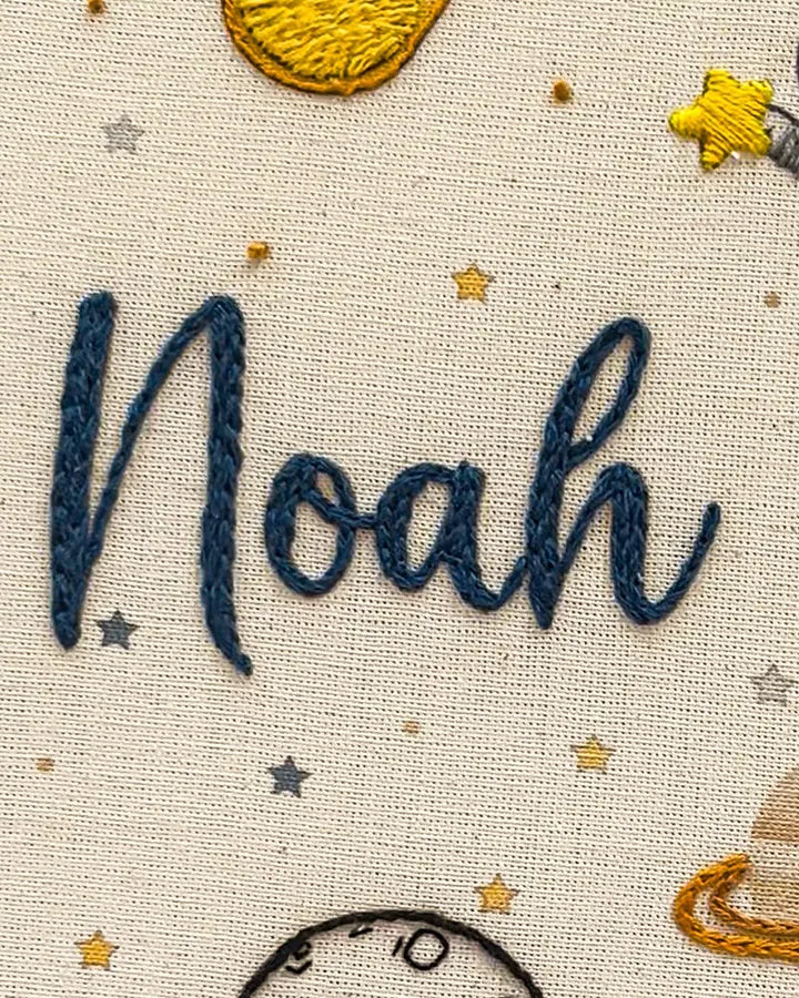 Embroidery of the name on a fabric with stars and planets
