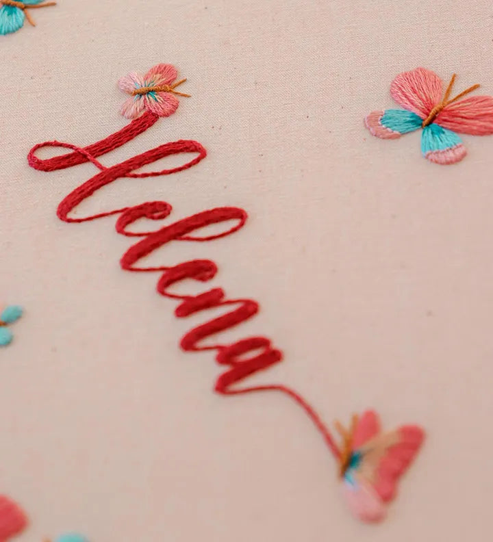 Hand stitched flower with clock displaying coral flowers and dancing butterflies