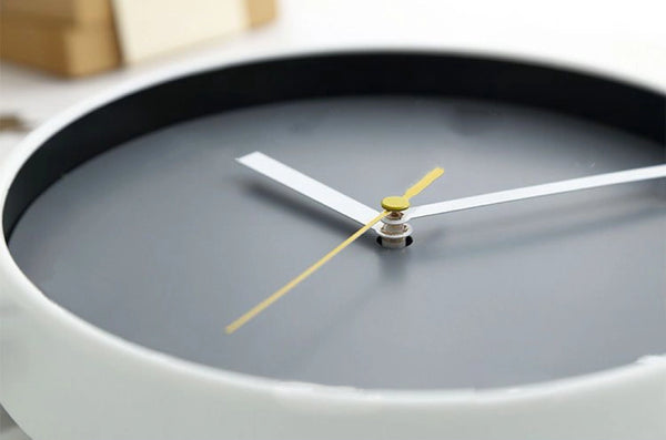 Close-up of a clock with a gray face and white and gold hands.