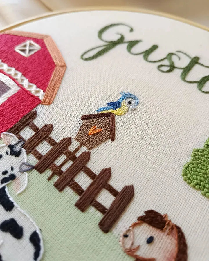 Embroidery hoop with farm-themed design including a barn, animals, and text.