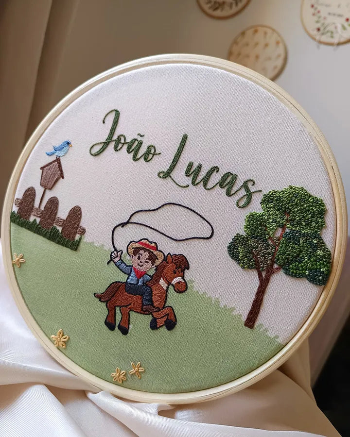 Embroidery hoop with a child riding a horse, tree, and birdhouse design, featuring the name
