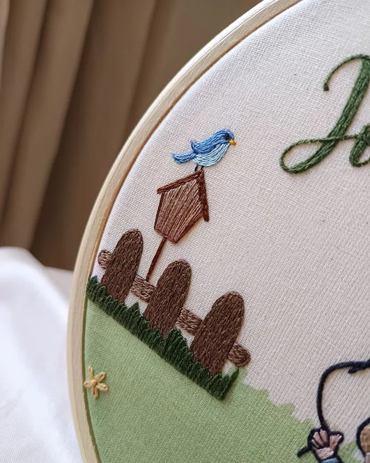 Embroidery hoop with a birdhouse and bluebird design on fabric